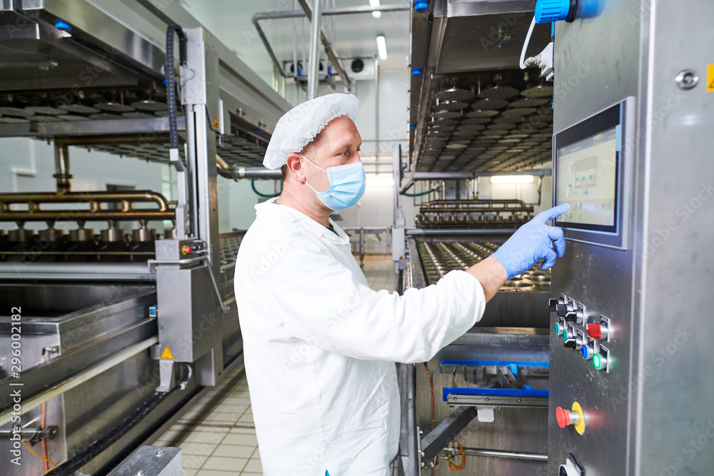 Stockfoto worker operates forming machine at cheese food production factory | Adobe Stock